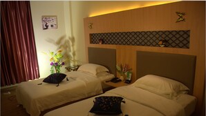 Een hotelkamer met twee bedden, een nachtkastje, een vaas met bloemen en een wandplank met decoratieve objecten.