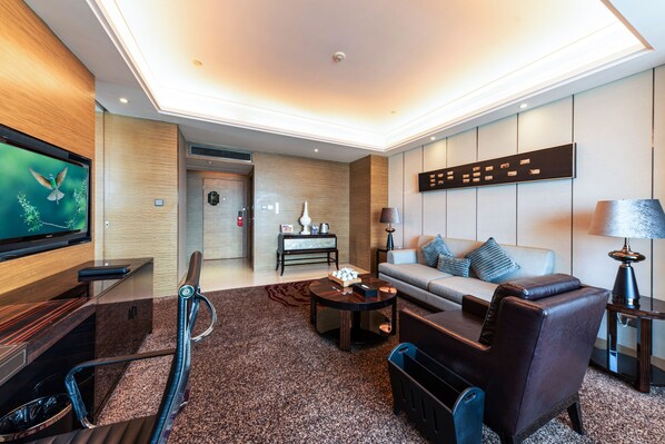 Un moderno vestíbulo de hotel con sofá, sillones, televisor, escritorio y recepción.