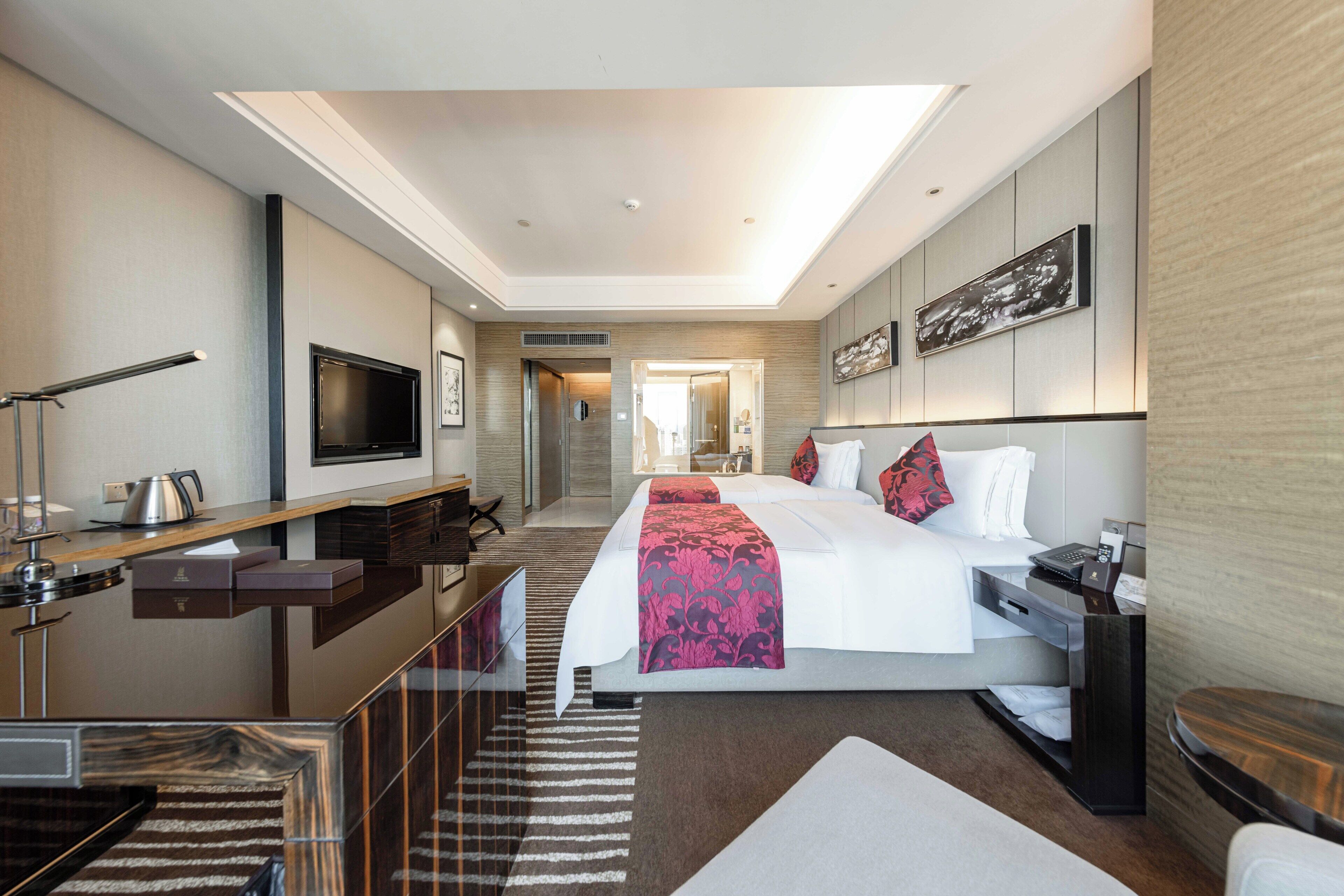 Una habitación de hotel moderna con una cama grande, un escritorio con televisor de pantalla plana, una cafetera y vistas al pasillo.