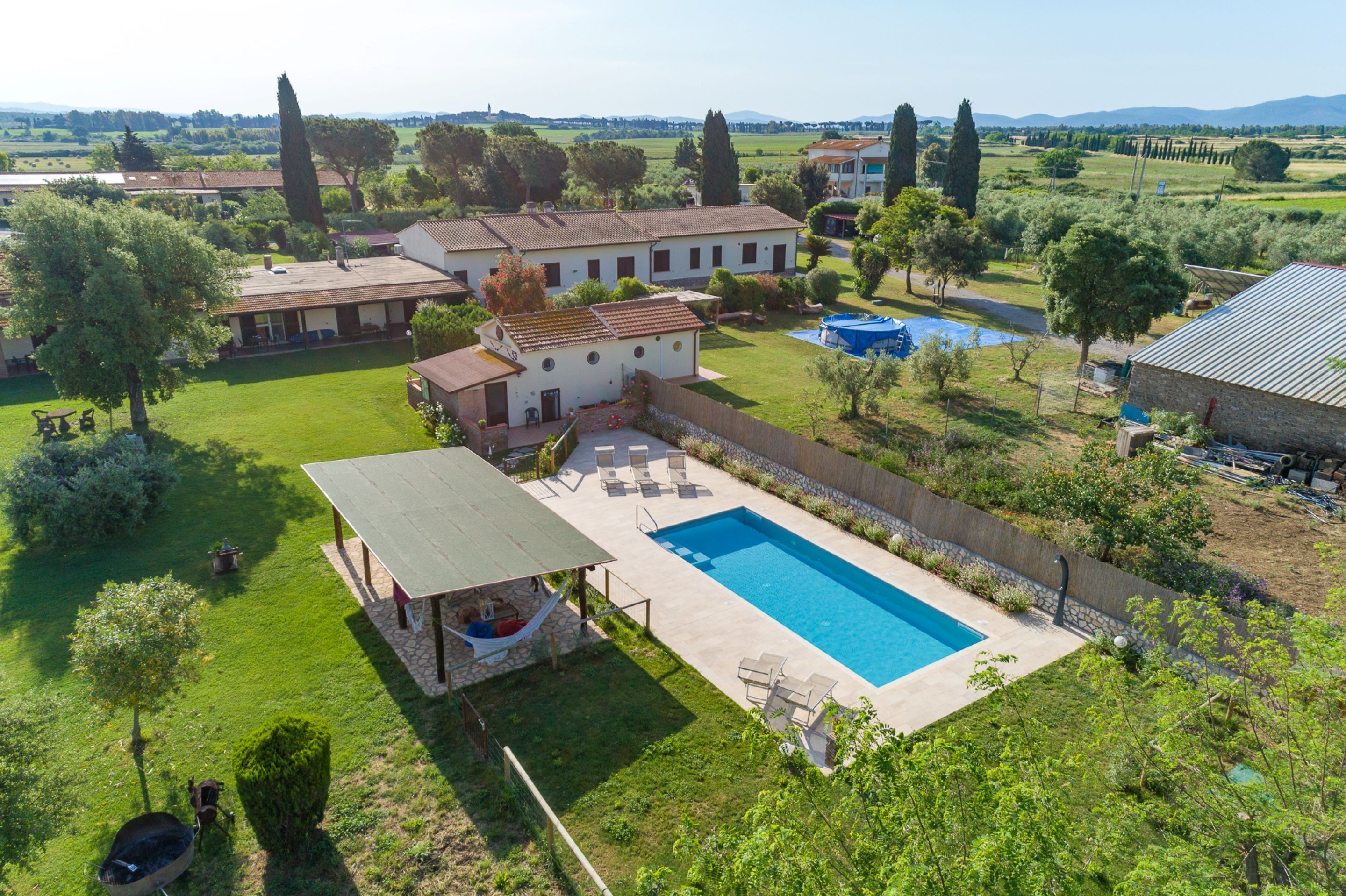 A large house with a swimming pool, a covered patio, and a garden.