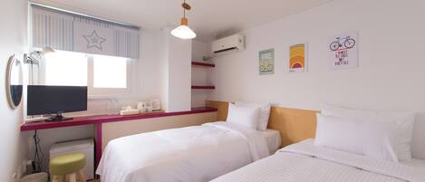A hotel room with two beds, a desk with a computer, a chair, and wall decorations.