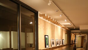 A hallway with wooden paneling, framed pictures on the wall, and potted plants along the floor. - Travel Monster (Seoul)