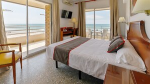 A hotel room with a bed, a desk, a chair, and a TV. The room has a balcony with a view of the beach. - Hotel Polamar  (Santa Pola)