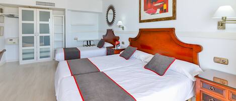 Habitación de hotel con una cama grande, una mesita de noche de madera, un escritorio y un armario con puertas de cristal.