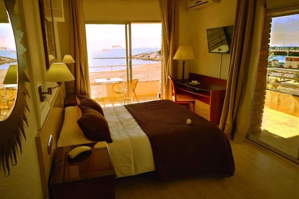 A hotel room with a bed, desk, and a view of the beach.