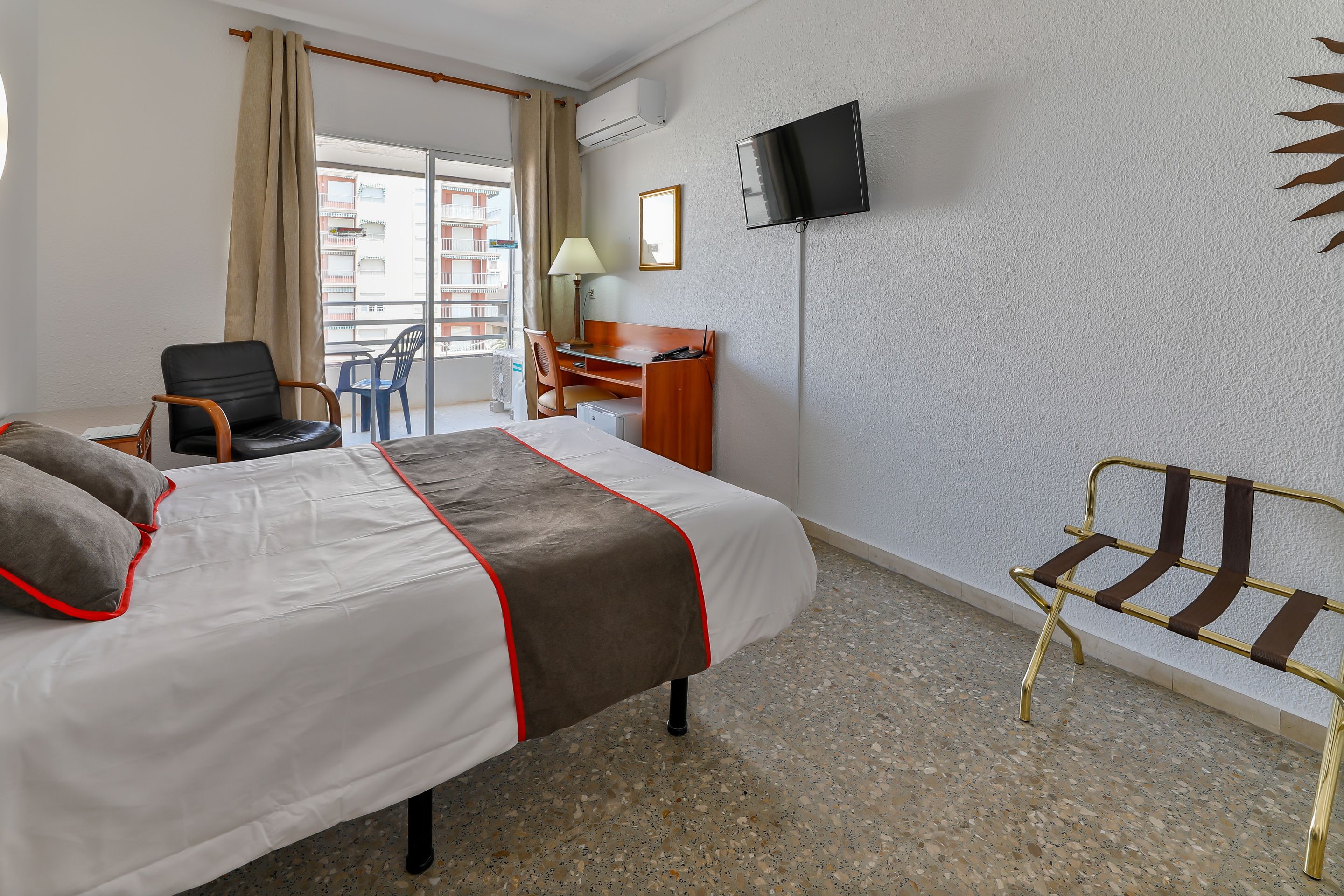 Une chambre d’hôtel avec un lit, un bureau, une chaise, une télévision et un balcon donnant sur une vue agréable.