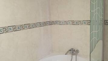 Une salle de bain moderne avec une baignoire sur pieds, une douche à parois de verre et des bordures décoratives en carrelage.