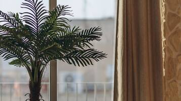 Una planta de palma en maceta y un globo terráqueo sobre una mesa de madera junto a una ventana con cortinas.