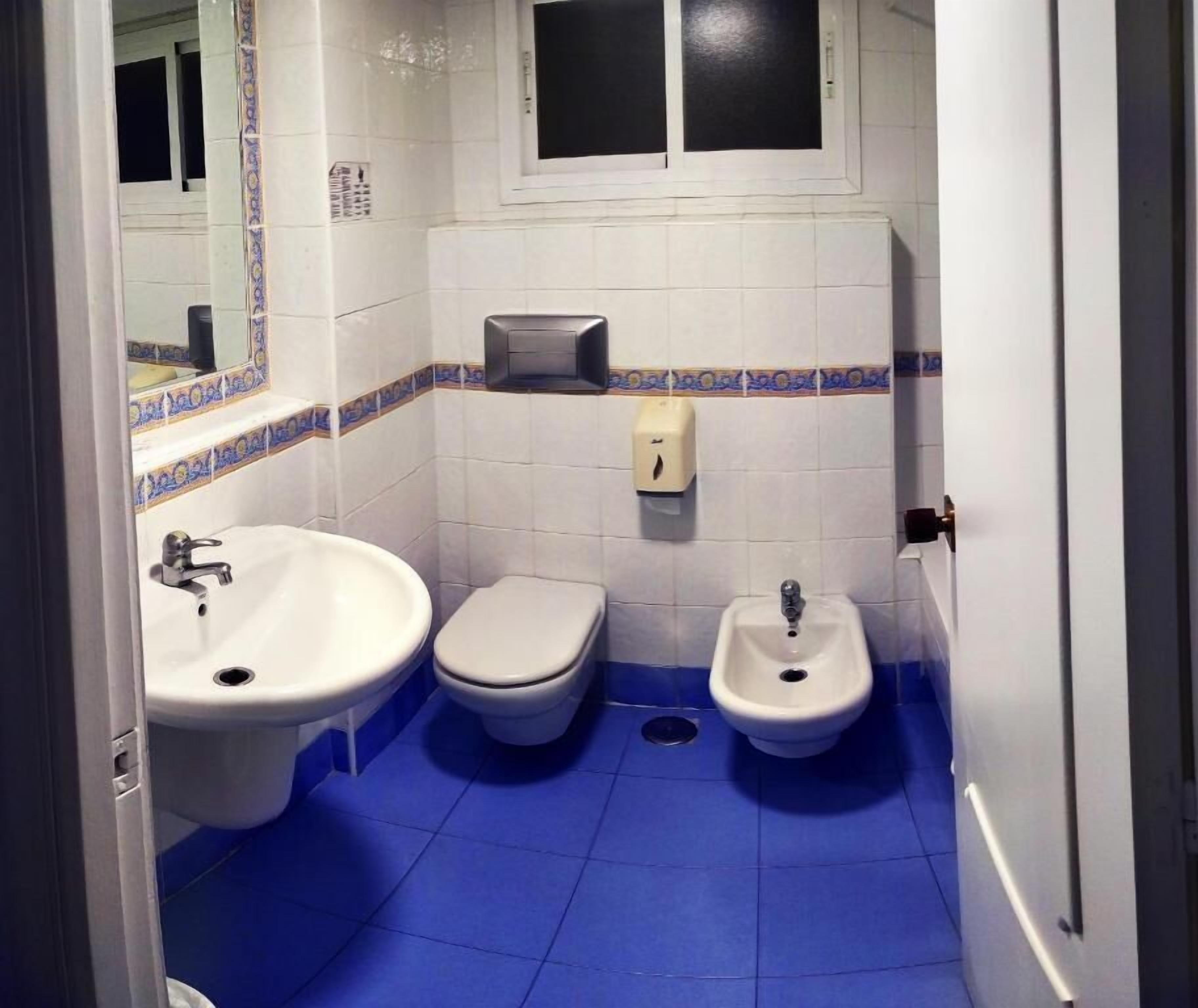 Un baño con dos inodoros, un bidé y un lavabo.