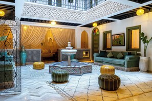 Un salón espacioso con techo alto, detalles decorativos y un sofá verde.