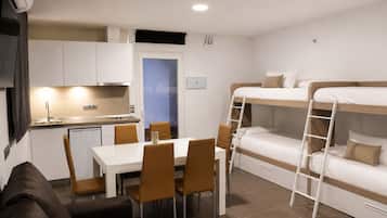 Habitació d'hotel compacta amb llits superposats, cuina americana, zona de menjador i un petit sofà.