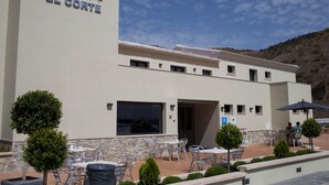 A hotel named "Hotel El Corte" with outdoor seating and a stone facade.