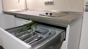 A kitchen with a built-in sink, a dish drying rack, and a drawer with utensils.