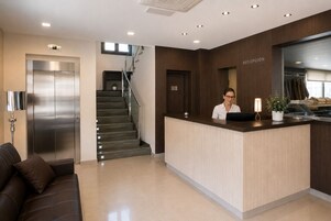 Zona de recepción con mostrador, escalera y perchero.
