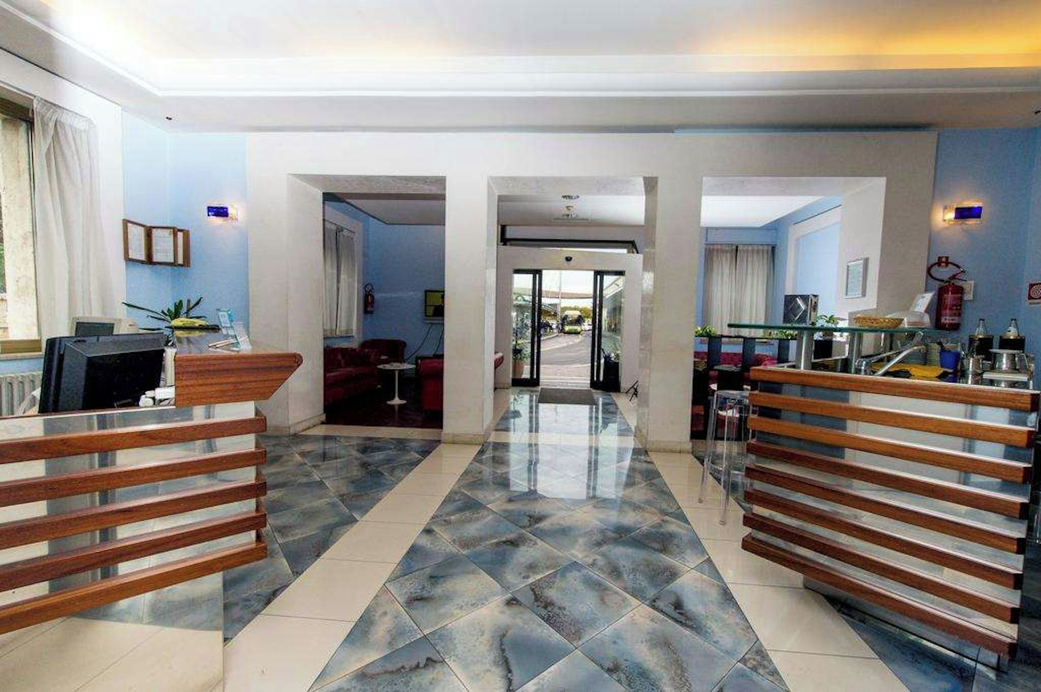 A hotel lobby with a reception desk, seating area, and a view of the street.