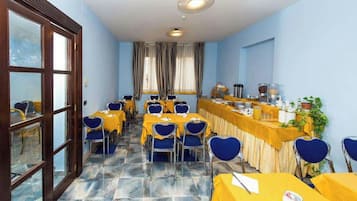 A conference room with tables and chairs, a buffet area, and a view through a window.