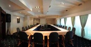 Una sala conferenze con un lungo tavolo, sedie e un proiettore.