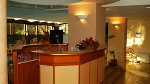 A bar area with a wooden counter, bar stools, and a potted plant with red flowers.