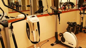 A gym with various exercise equipment including a stationary bike, elliptical trainer, and rowing machine. - Millenium Palace (Ohrid)