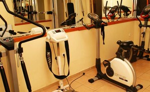 A gym with various exercise equipment including a stationary bike, elliptical trainer, and rowing machine. - Millenium Palace (Ohrid)