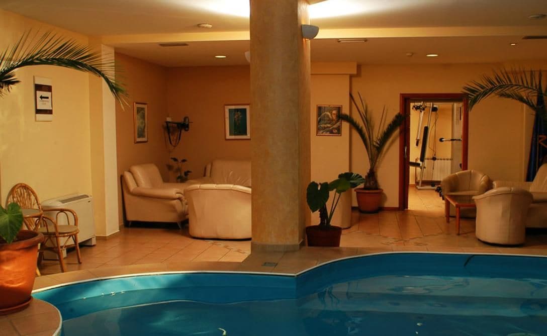 A pool area with a large column, several chairs, and potted plants.