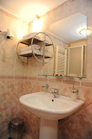 Casa de banho com lavatório, um porta-toalhas, espelho e um cesto de lixo.
