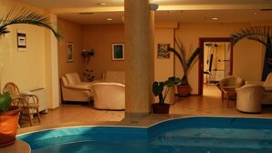 A pool area with a large column, several chairs, and potted plants.