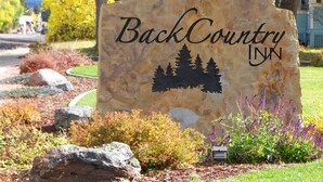 A stone sign with the text "BackCountry INK" and a silhouette of trees. - BackCountry Inn (Norwood)
