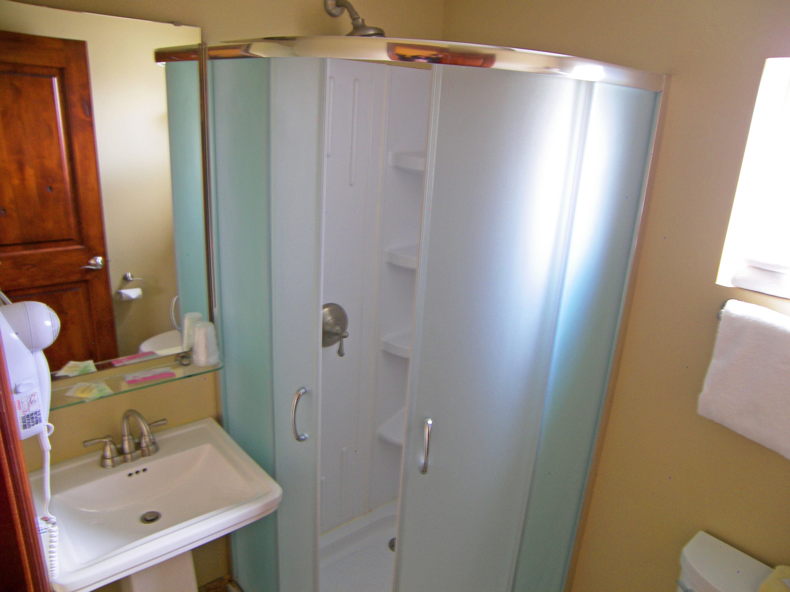 A bathroom with a white sink, a mirror, and a shower enclosure.