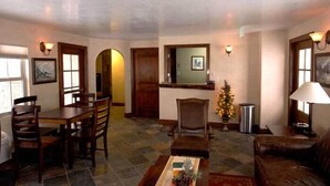 A living room with a dining table, chairs, a coffee table, a fireplace, and a Christmas tree. - BackCountry Inn (Norwood)