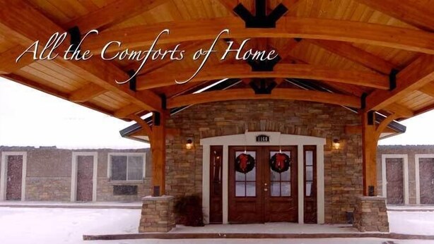 A covered entrance with stone walls and wooden beams, featuring a double door with wreaths. - BackCountry Inn (Norwood)