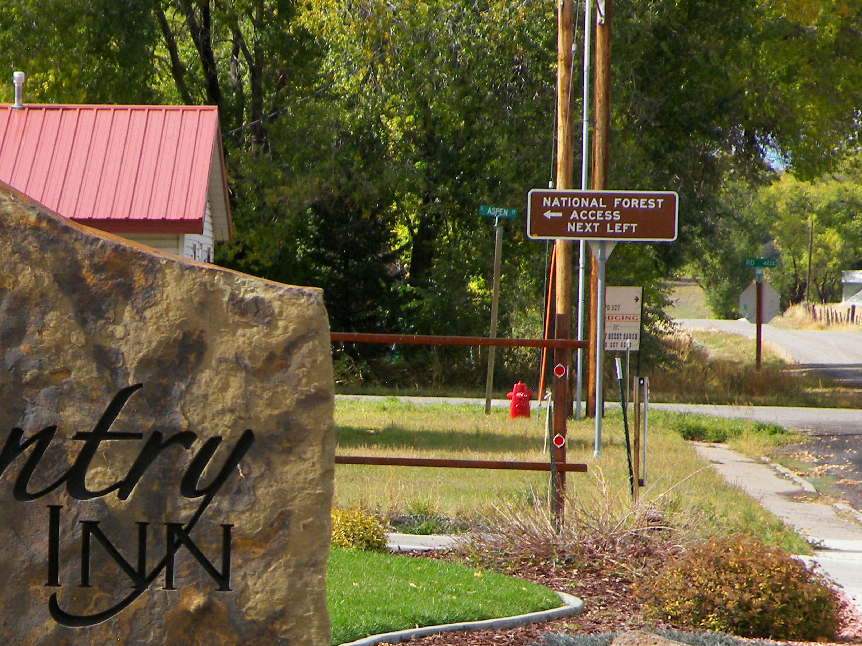 A stone sign with the inscription "INN" and a road sign indicating "NATIONAL FOREST ACCESS NEXT LEFT".