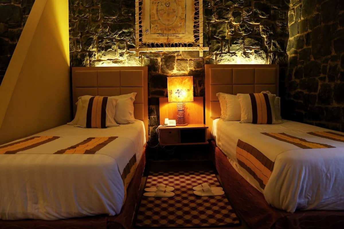 A room with two beds, a stone wall, a map, and a checkered floor.