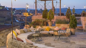 An outdoor seating area with stone walls, cushioned seating, and a pergola structure. - Dere Suites (Ürgüp)
