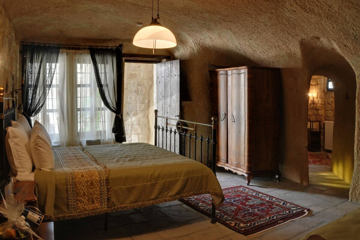 Un dormitorio con una cama grande, un armario de madera y una pared de piedra.