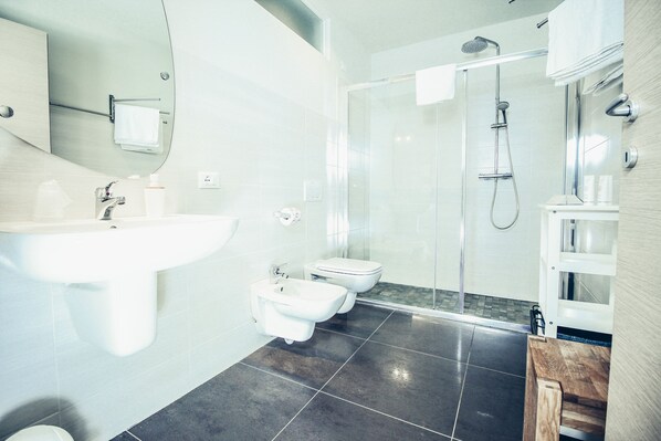 A modern bathroom with a large sink, bidet, and glass-enclosed shower.