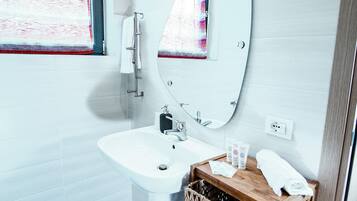A modern bathroom with a white sink, mirror, and a wooden vanity.