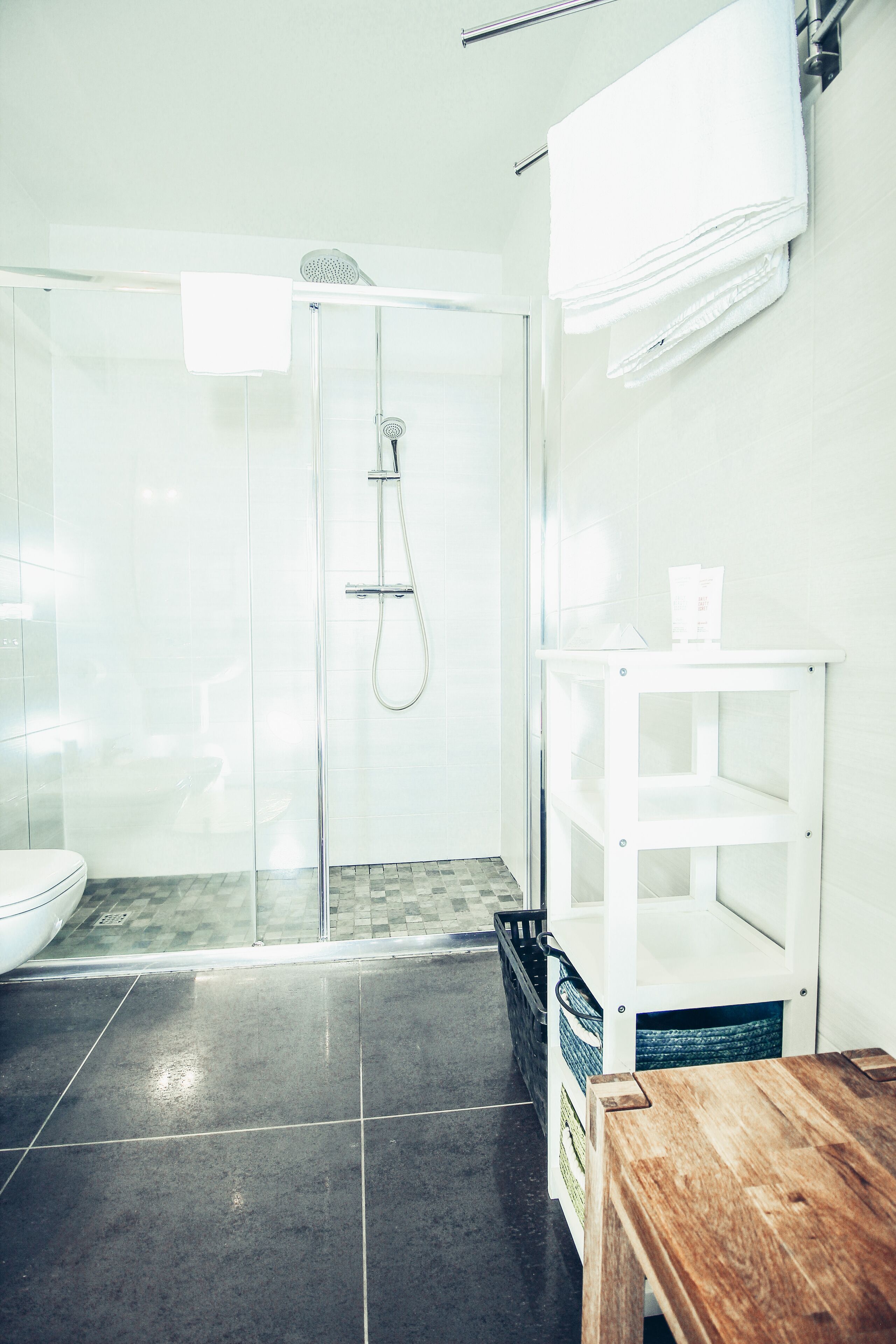 A modern bathroom with a glass shower enclosure, a white sink, and a wooden vanity.