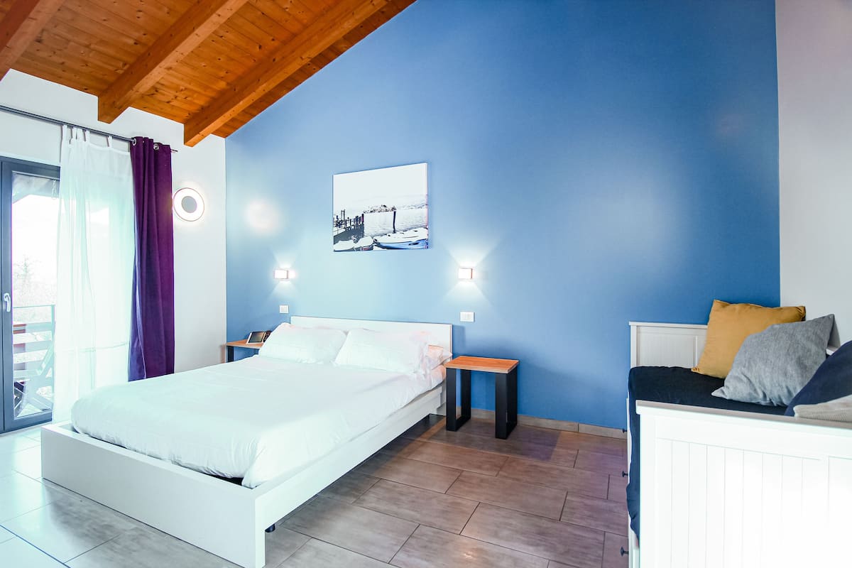 Um quarto com cama, mesa de cabeceira, escrivaninha e cadeira.