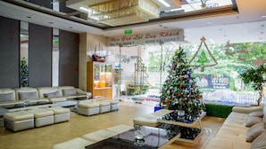 A modern hotel lobby with a Christmas tree, seating areas, and a large window with a view. - Dendro Hotel (Nha Trang)