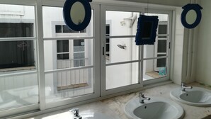 Ein Badezimmer mit zwei Waschbecken, einem Spiegel und einem Fenster mit Ausblick.