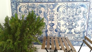 Eine Wand mit kunstvollen blauen und weißen Fliesen, eine Holzbank und eine grüne Pflanze.