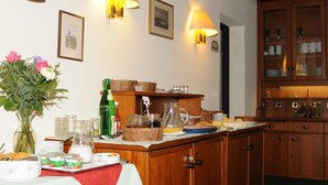 A breakfast bar with various food items and drinks, wooden cabinets, and wall-mounted lamps. - Hotel Rheingauer Tor (Hochheim am Main)