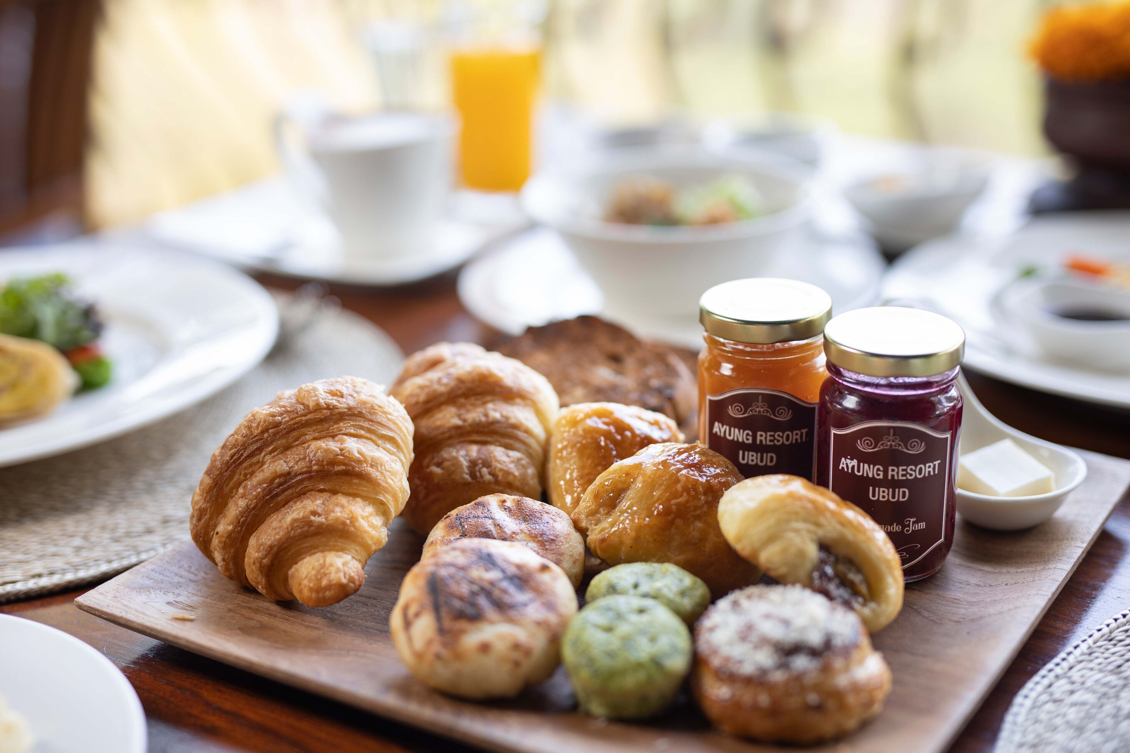 A breakfast spread with pastries and jams on a wooden board.