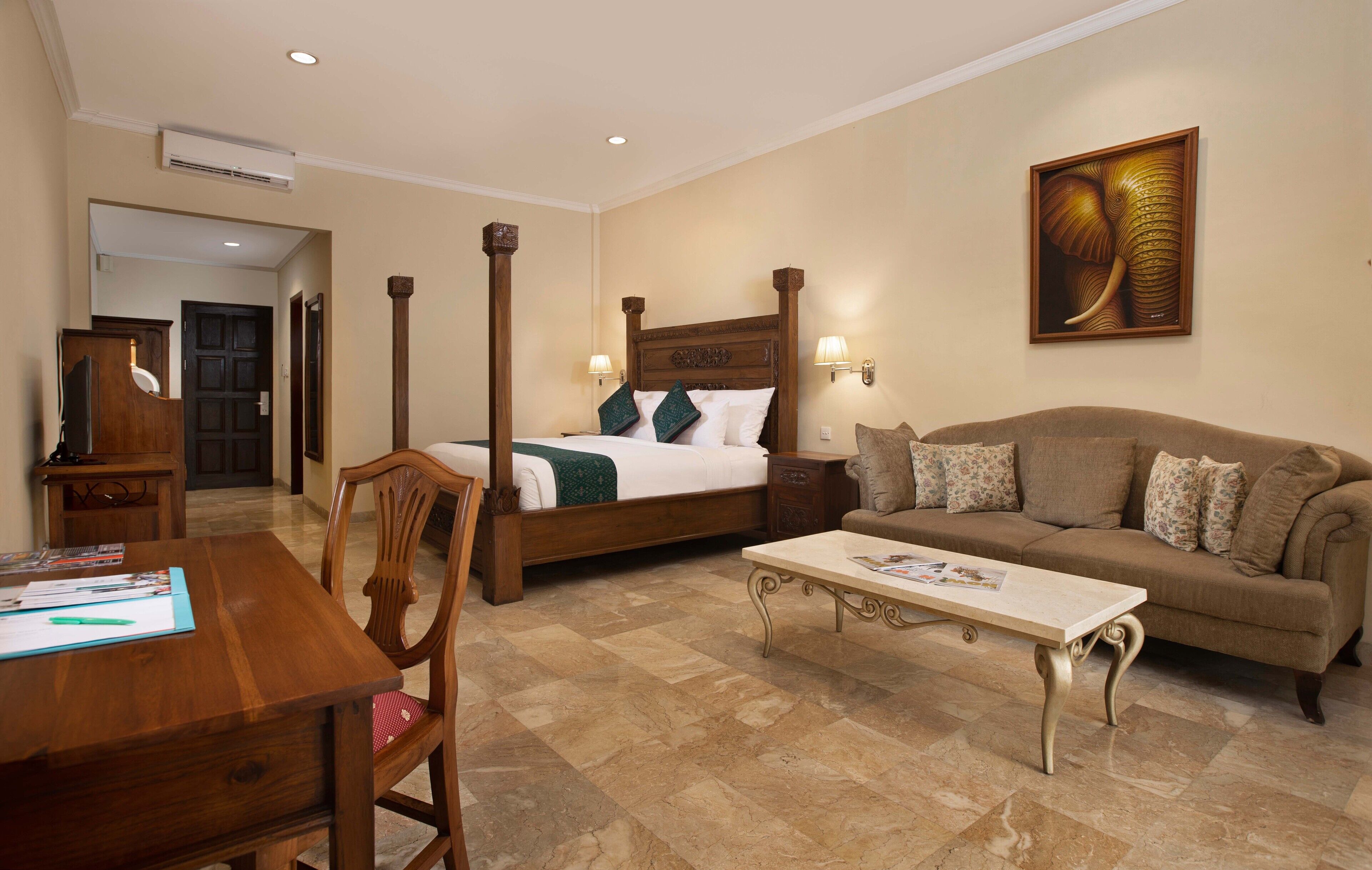 A hotel room with a bed, a sofa, a desk, and a coffee table.