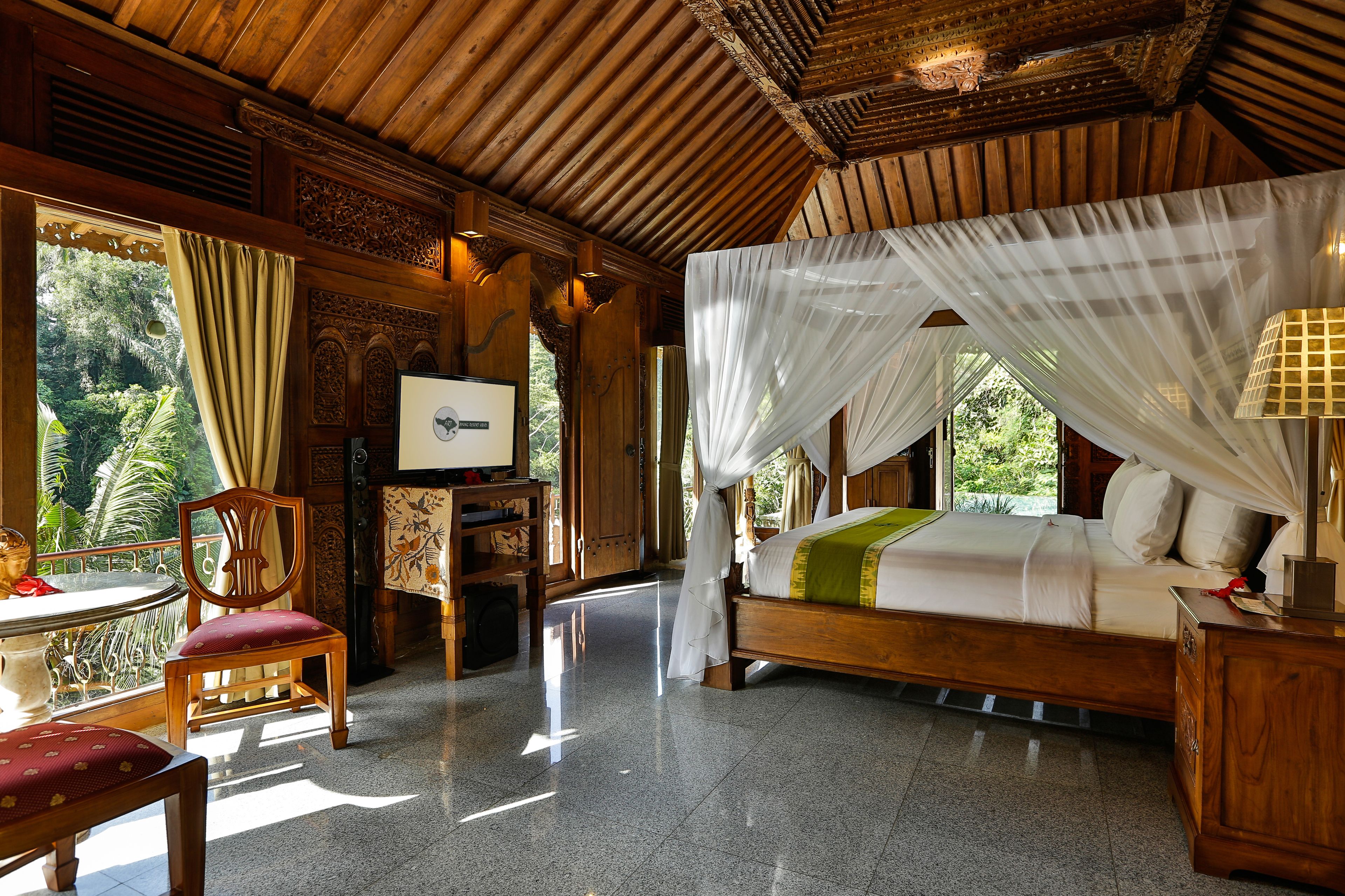 A room with a bed, a TV, a table, and chairs.