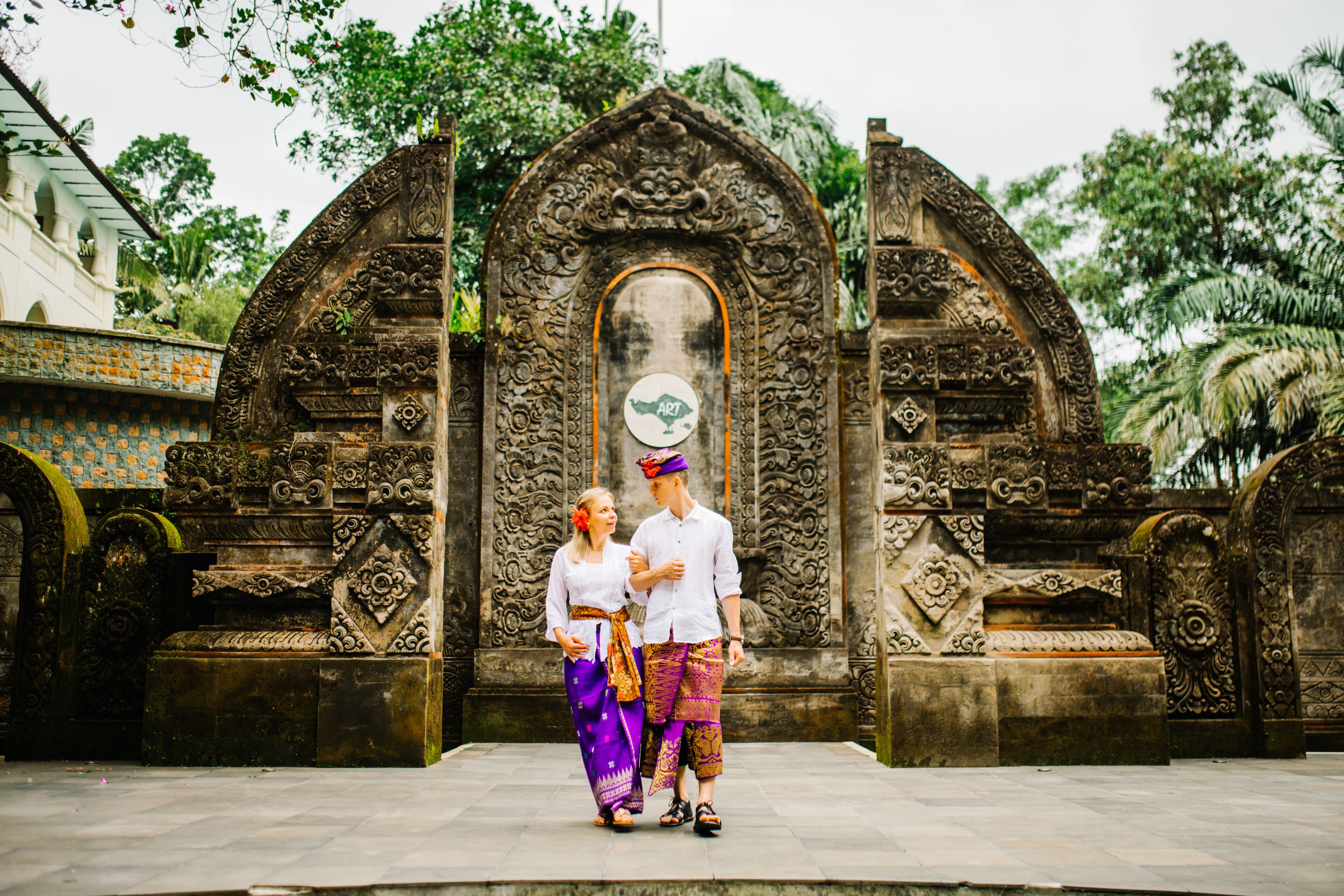 A couple standing in front of an ornate stone structure with intricate carvings.