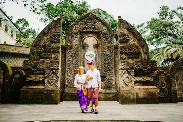 A couple standing in front of an ornate stone structure with intricate carvings. - Ayung Resort Ubud (Ubud)