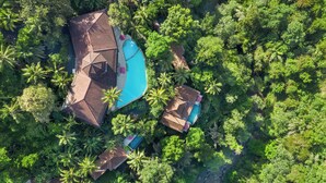 Vista aérea de un complejo turístico con varias edificaciones, una piscina y abundante vegetación.