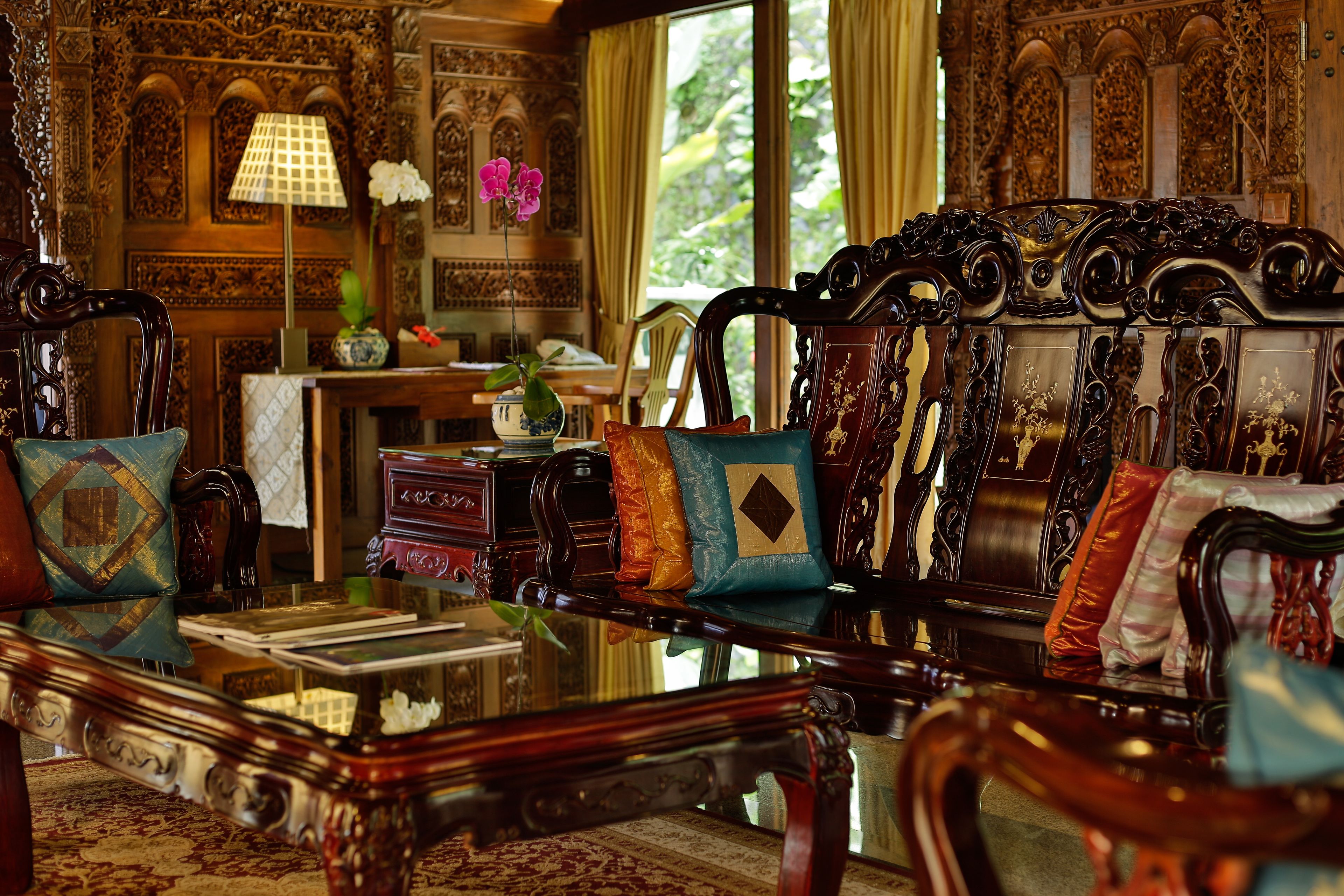 A room with ornate furniture, a table with books, and a vase with flowers.